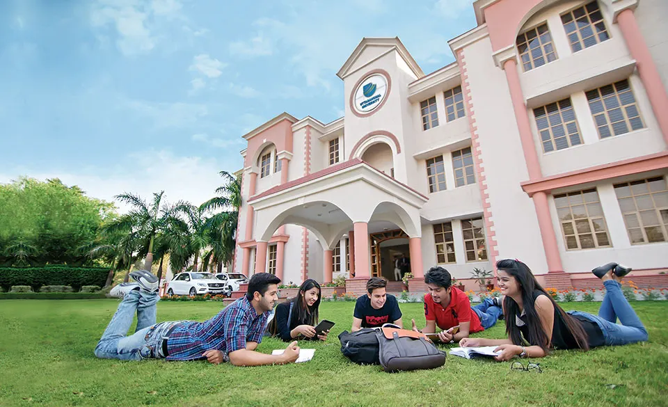 Students on the lawn in front of a campus building at Uttaranchal University